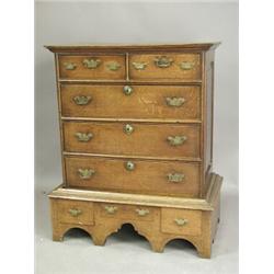 An 18th century low oak chest of drawers, with fielded panelled sides, on a stand with three d...