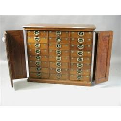 An American Ambergs Patent filing chest, in walnut with folding doors enclosing 24 letter fili...