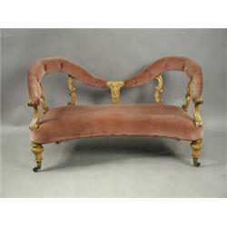 A Victorian maple two seat settee with a shaped back, carved decoration and turned and reeded...