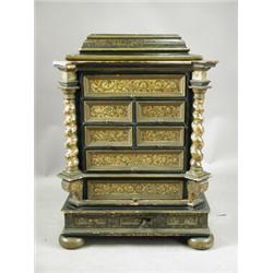 A continental ebonised and painted table cabinet, having an arrangement of seven drawers withi...