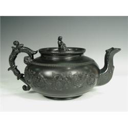 An early l9th century black basalt teapot with applied foliate scrolling decoration, impressed ma...