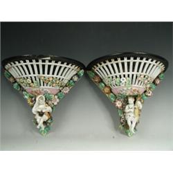 A pair of late 19th century continental porcelain wall brackets with applied putti and flowers, S...
