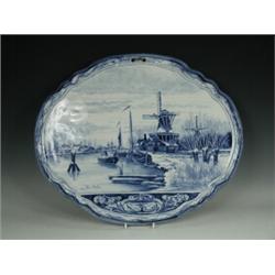 A large Edwardian oval Dutch Delft wall plaque with rural hand-painted decoration, signed Louis A...