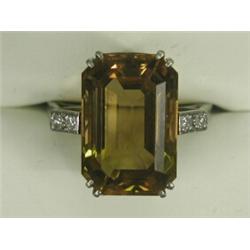 A solitaire citrine ring of 17 x 12mm with diamond set shoulders set in white metal (tests gold),...