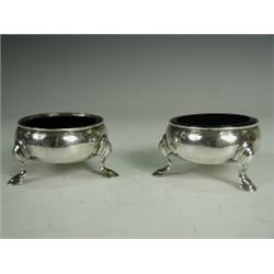 A pair of Victorian silver salts on three feet each with replaced blue glass liners, London 1859,...