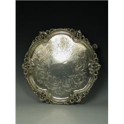 A Victorian silver salver with engraved scrolling decoration and open scrolling rim supported upo...