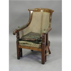 A Regency mahogany bergere reading chair with padded arms (pads missing) and brass fittings for r...