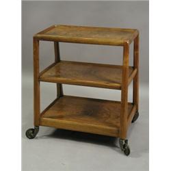 A 1950's walnut and plywood trolley of tapering form, the three graduated trays joined by chamfer...