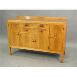 A 1950's Heals walnut sideboard with two central drawers and a two door cupboard, between a pair...