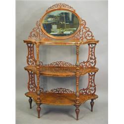 A Victorian burr walnut three tier whatnot surmounted with an oval mirror and with pierced fretwo...