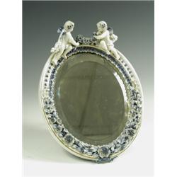 A J Roth mirror frame late 19th Century, the oval surround encrusted with blue and gilt flower...