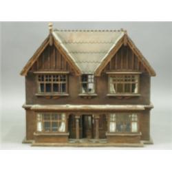 A wooden dolls' house in the form of a double fronted house with ground floor bay windows belo...