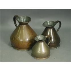 Three 19th Century copper measures, each of waisted bulbous form, having a flared lip and appl...