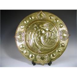 An Art Nouveau embossed brass plaque with a grotesque beast profile to the centre, framed by b...