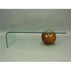 A modern glass coffee table supported with a wooden ball, 130cm long Est. 150/200...