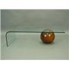 Image 1 : A modern glass coffee table supported with a wooden ball, 130cm long Est. 150/200...