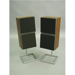 A pair of Bang & Olufsen speakers in rosewood veneered cases, raised on stands Est. 50/80...