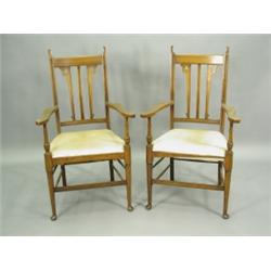 A pair of 'Arts & Crafts' walnut elbow chairs, each with three back splats and shaped flat arm...