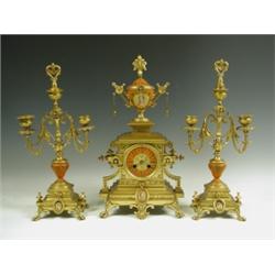 A late 19th Century gilt bronze clock garniture, mounted with porcelain vases and plaques, and...