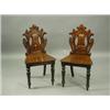 A pair of Victorian pierced mahogany hall chairs with 'C' scroll decoration, shaped seats and...