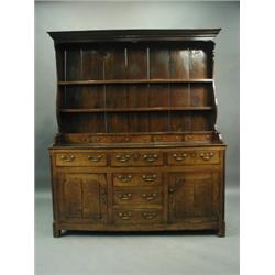 A George III oak Welsh dresser, the moulded cornice over three graduated shelves and five spic...