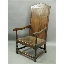 An 18th Century oak armchair, with a framed plank back on turned legs and all round stretchers...