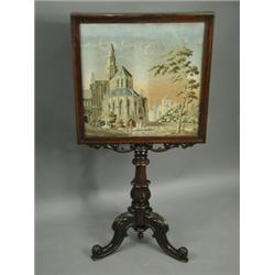 A Victorian rosewood firescreen, the woolwork picture depicting a continental church and figur...