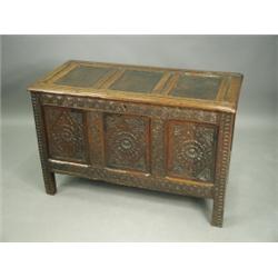 An oak coffer, with a three panelled lid, carved stile and frame and lozenge and rosette carve...