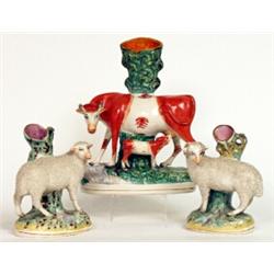 A Staffordshire pottery figure group of a cow and calf, circa 1870, the standing cow in orange sp...