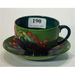 Moorcroft leaf and berry onto a green background patterned cup and saucer, W.M. and Moorcroft mar…