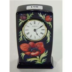 Moorcroft floral patterned clock onto a blue background, impressed Moorcroft and W.M. mark to bas…