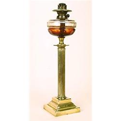 A late 19th century brass oil lamp, with clear facetted glass reservoir, on a Corinthian column w...