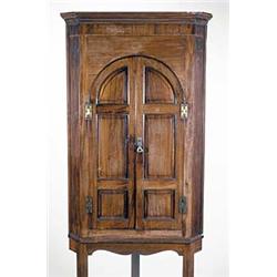 An early 19th century mahogany hanging corner cupboard, on a later stand, the moulded cornice abo...