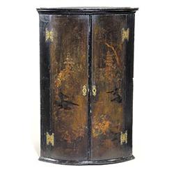 An early 19th century japanned bowfronted hanging corner cupboard, with oriental landscapes on a...