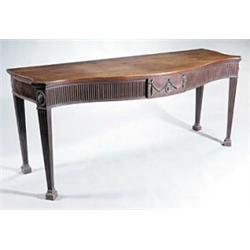 A mahogany serving table in George III style, the serpentine top above a fluted frieze with a cen...