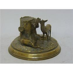 AN EDWARDIAN BRASS INKSTAND, modelled as two deer grazing beside a tree stump forming the ink con...