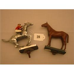 Two car mascots, one silver plated horse with jockey in riding colours, the other of chestnut hor…