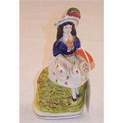 19th Century Staffordshire figure of a girl seated on a rock and holding a bird's nest, 15cm high...