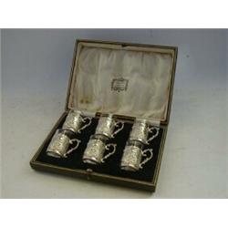 A CASED SET OF SIX DEMITASSES, relief silver sleeves with country scenes, maker RB, Sheffield 191...
