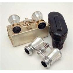 Two pairs of French mother of pearl opera glasses, one with silvered mounts, the other gilt mount...