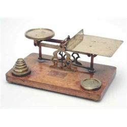 A large late Victorian brass postal scale, on oak base, with seven weights, 13ins wide...