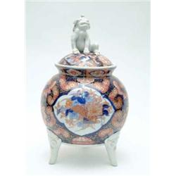 A 19th century Imari porcelain vase, of spherical shape, on three mask feet, domed cover with Dog...