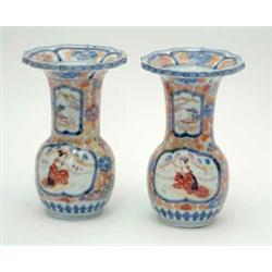 A pair of Japanese Imari vases, with flared and scalloped rims, decorated with panels amid foliag...