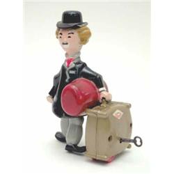 A plastic clock work figure of a gent carrying luggage 6.25ins...