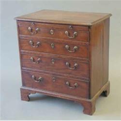 A small George III mahogany chest of four graduated drawers fitted brushing slide on bracket feet...