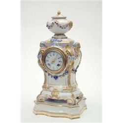 A KPM porcelain mantel clock, modelled with urn surmount, mask terminals and floral and ribbon dr...