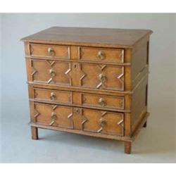 A Jacobean oak two section chest of four drawers with geometric panelled fronts and replaced hand...