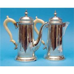 A pair of George VI silver cafe au lait pots, of George III design with ivory scroll handles, Mak...