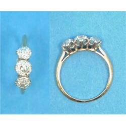 A three stone diamond ring, the old brilliant cut stones claw-set in 18ct gold....