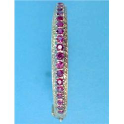 A gold hinged bangle, with engraved and pierced work decoration, the front claw-set with a row of...